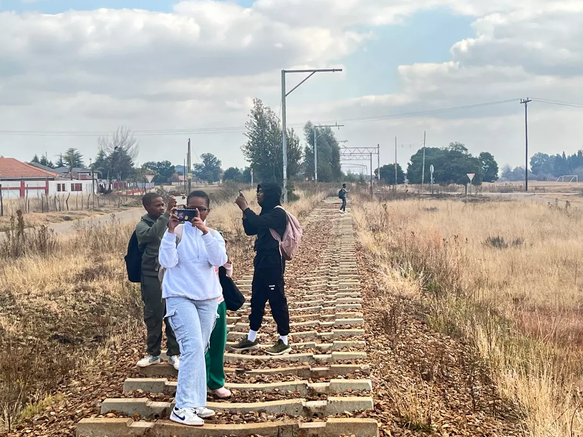 Three young people taking photos on a disused railway track