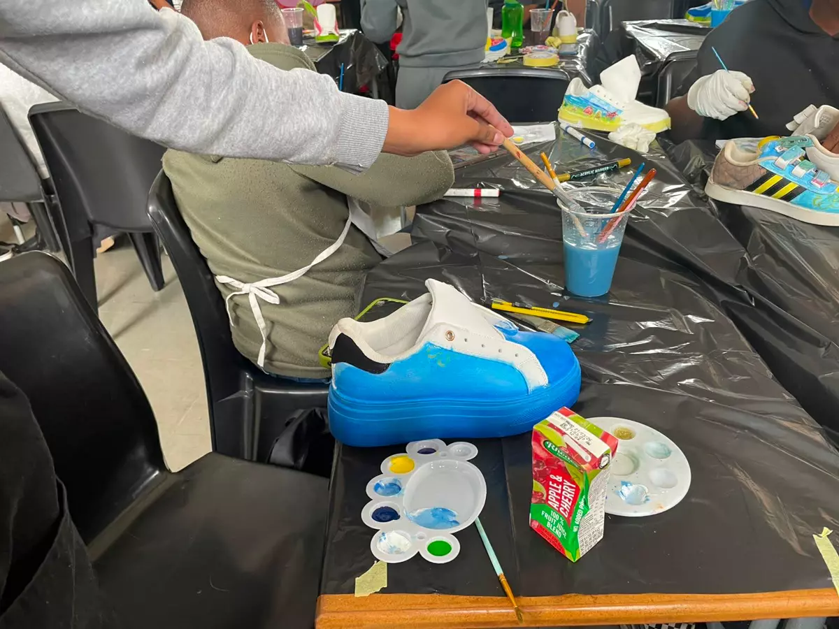 People customizing sneakers with paint at a workshop table