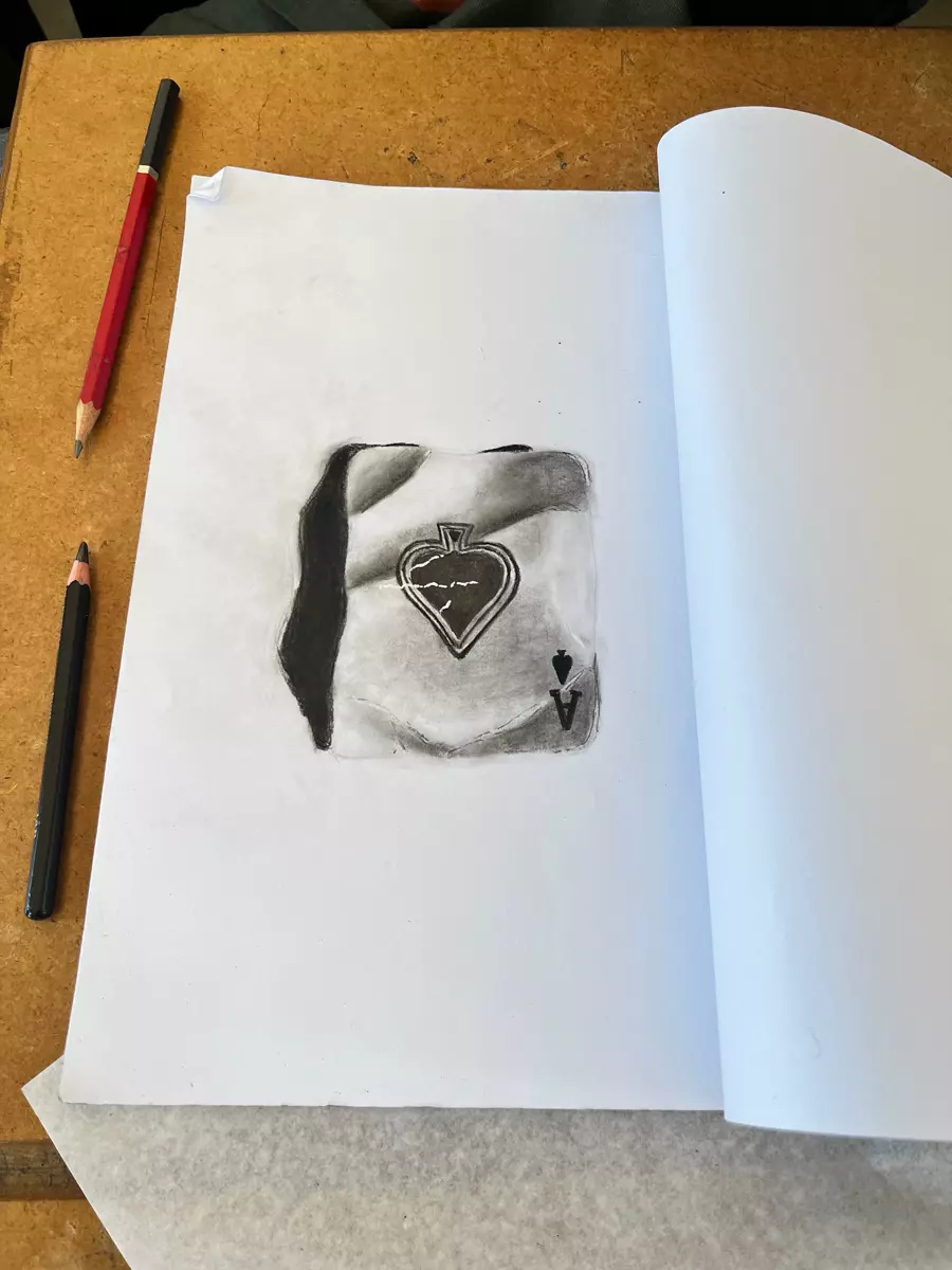 A charcoal drawing of an ace of spades playing card in a sketchbook