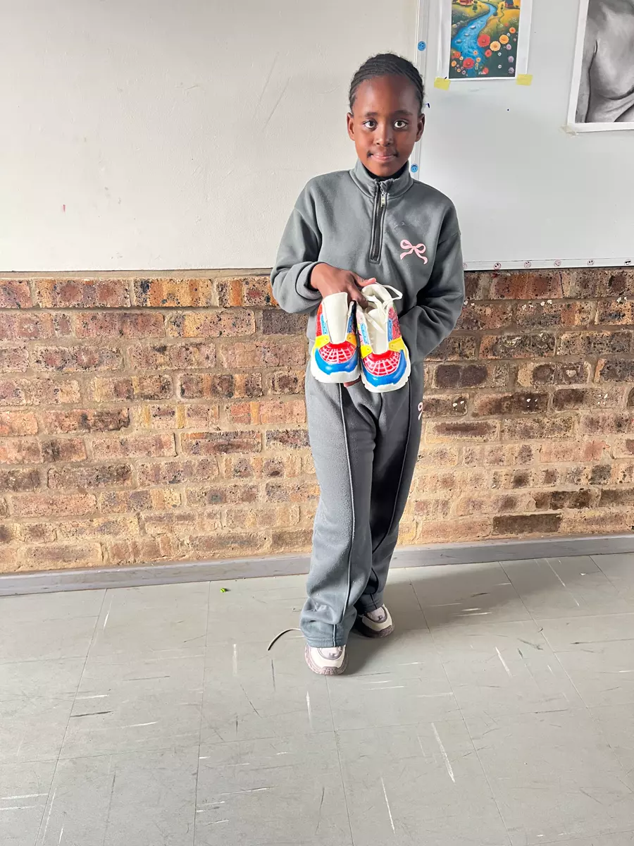 A young girl holding up a pair of colourful custom sneakers