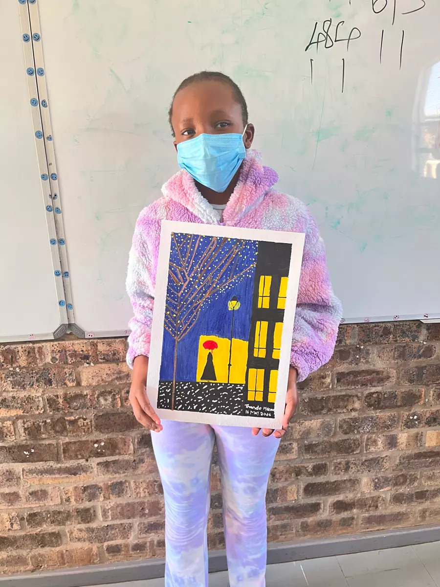 A young girl in a blue mask and tie-dye hoodie holding up a painting
