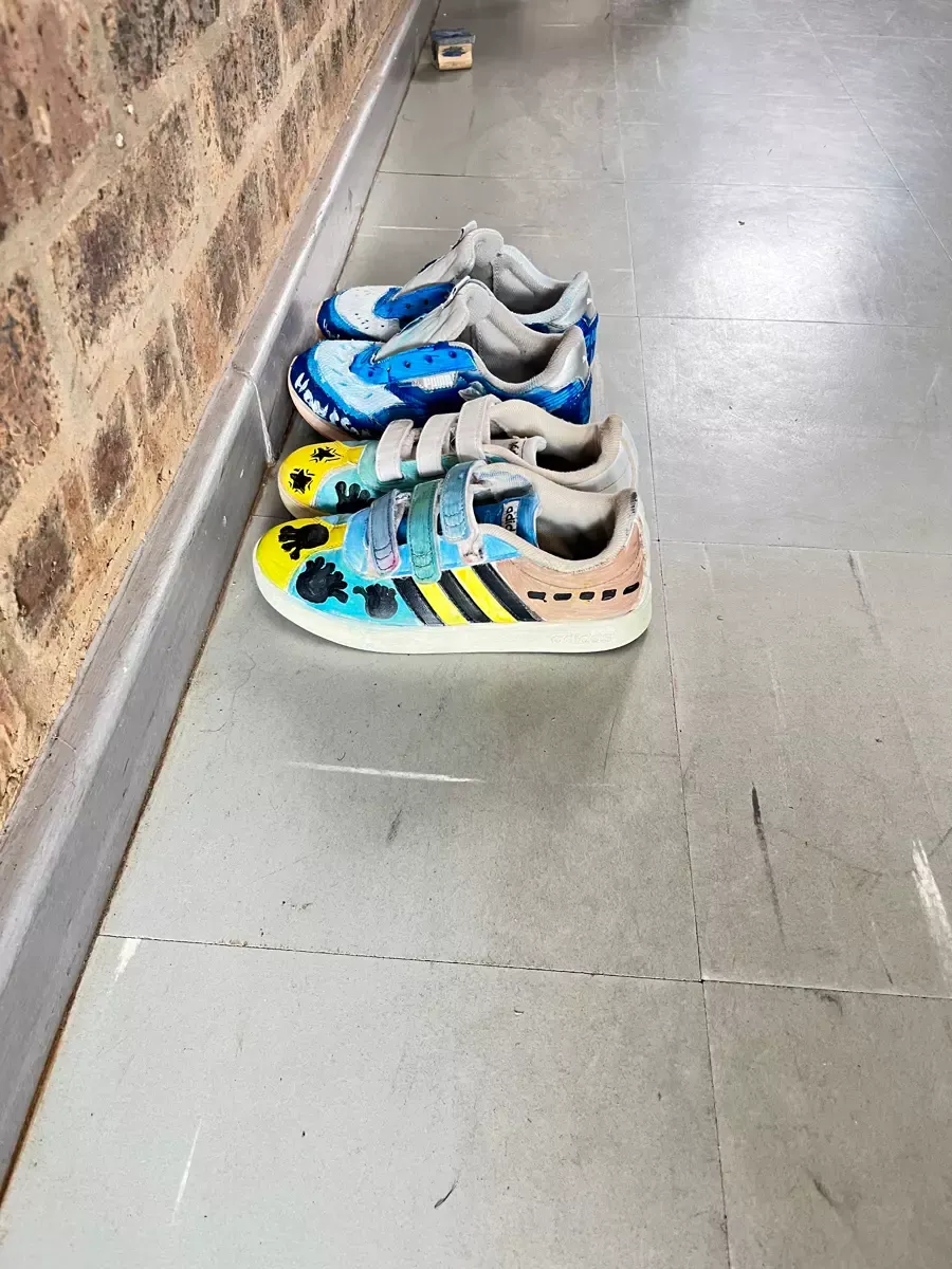 Custom-painted children's shoes lined up against a brick wall