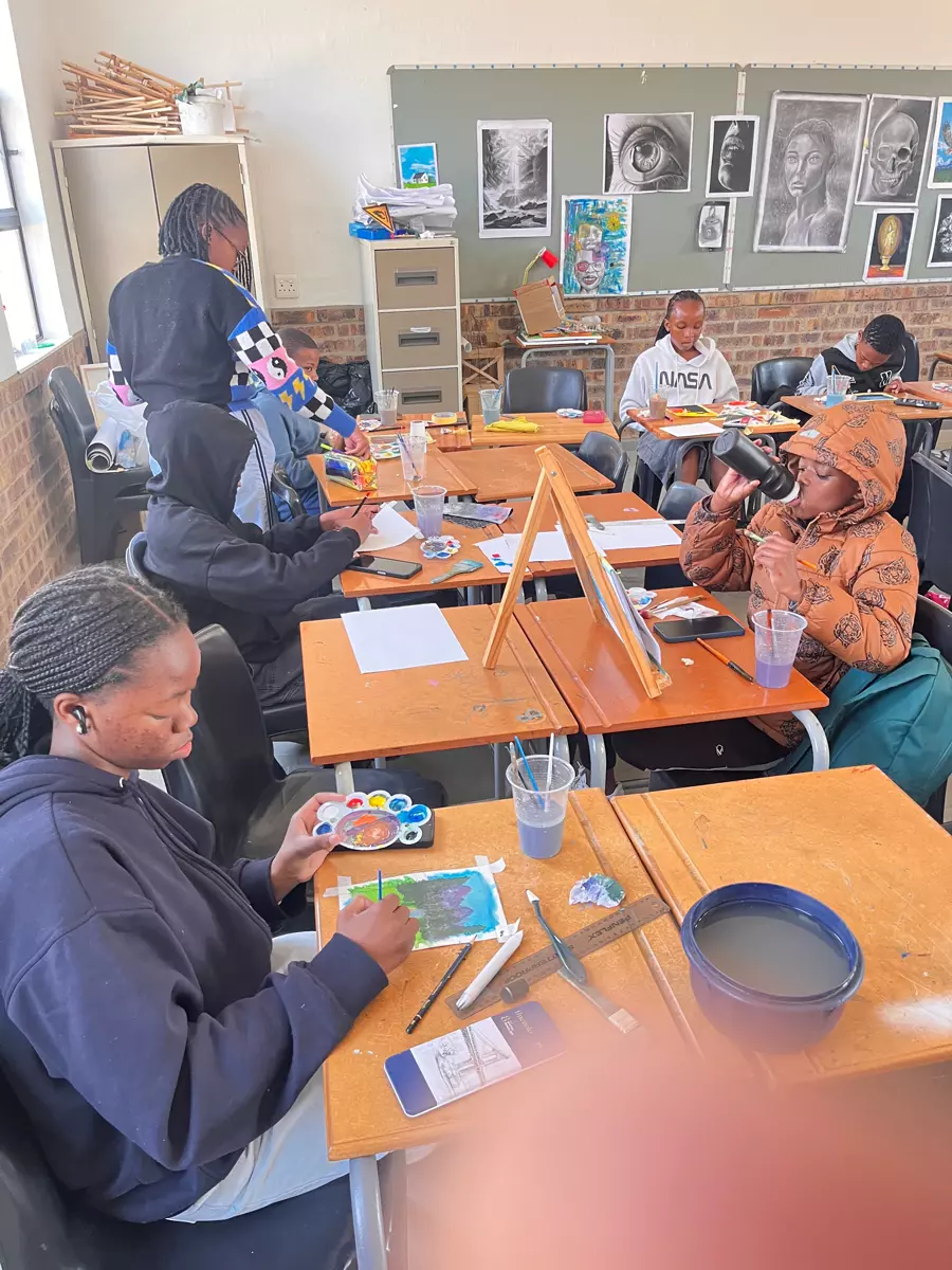 Students painting at desks in an art classroom